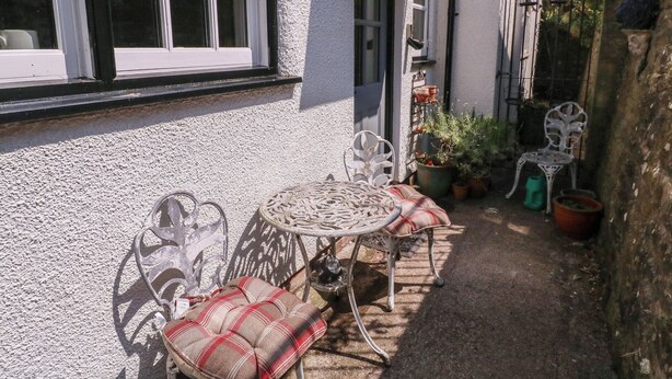 A patio with a table and chairs, potted plants, and a small garden area. - 19 Lion Street (Hereford)