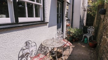 A patio with a table and chairs, potted plants, and a small garden area.