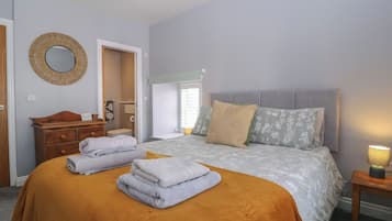 A bedroom with a bed, a dresser, a mirror, and a bedside lamp.