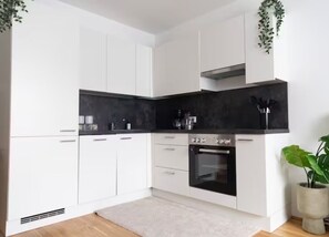 A modern kitchen with white cabinets, a black countertop, and an oven.