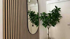 Une salle de bain avec un mur recouvert de lambris en bois, un grand miroir ovale et une plante en pot.