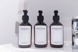 Three bottles of bath essentials: shampoo, hand soap, and shower gel.