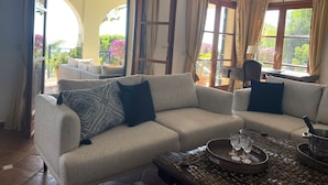 A spacious living room with a sofa set, a coffee table, and a view of the outdoor balcony.
