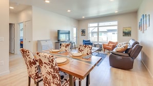 A spacious living area with a dining table set for four, a leather sofa, and a television in the background. - Modern Livingston Condo Near Yellowstone River! (Livingston)