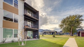 A modern two-story building with a balcony, a well-maintained lawn, and a clear sky. - Modern Livingston Condo Near Yellowstone River! (Livingston)