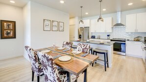 A modern kitchen with white cabinets, stainless steel appliances, and pendant lighting. - Modern Livingston Condo Near Yellowstone River! (Livingston)