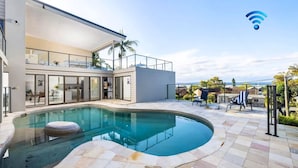 Una casa moderna con piscina, mobili da esterno e vista sul mare.