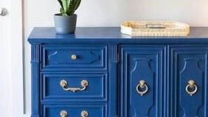 Un aparador azul con detalles dorados, una planta en maceta y un televisor de pantalla plana en la parte superior.