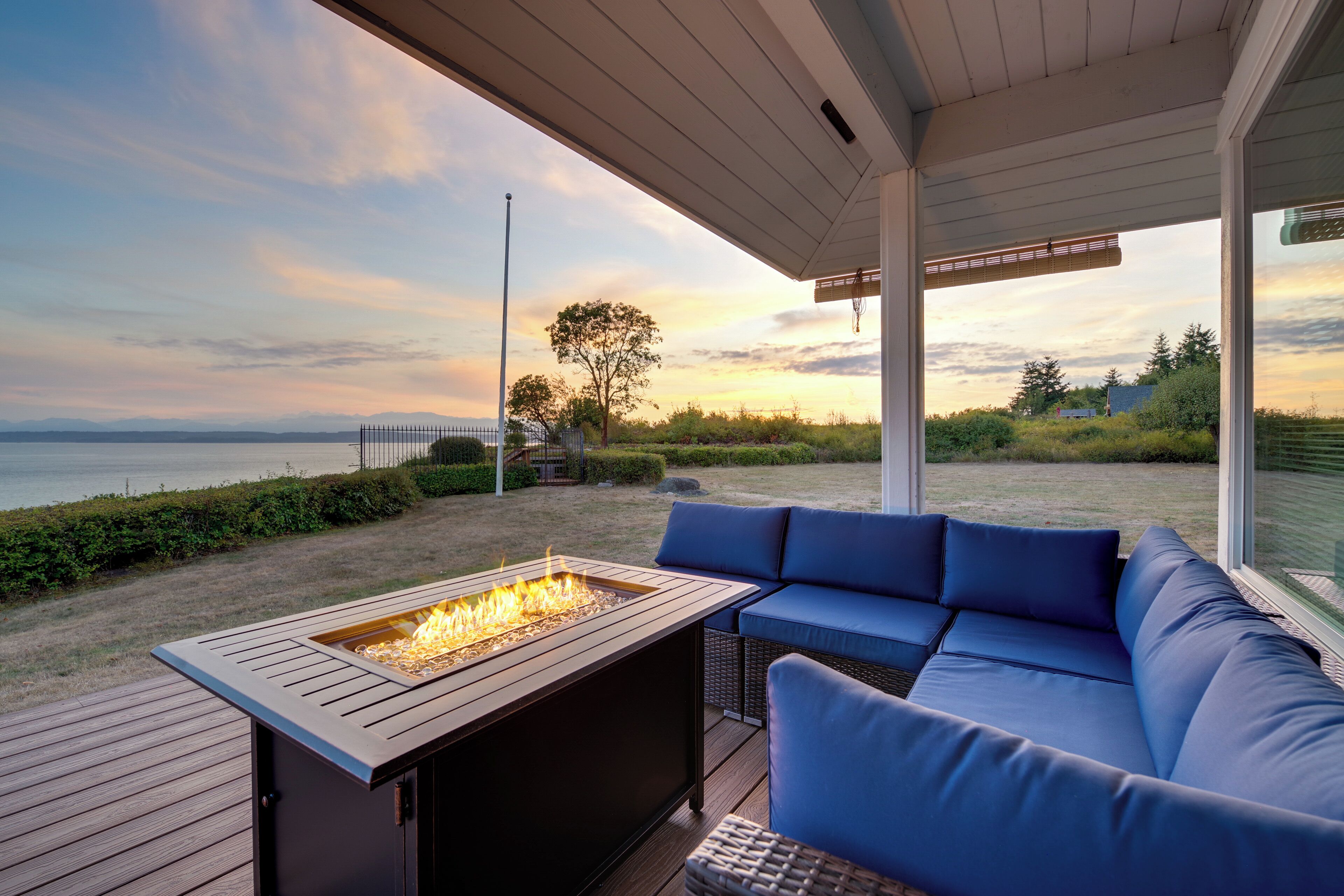 Una terrazza con un braciere, arredi da esterno blu e vista sull'oceano.