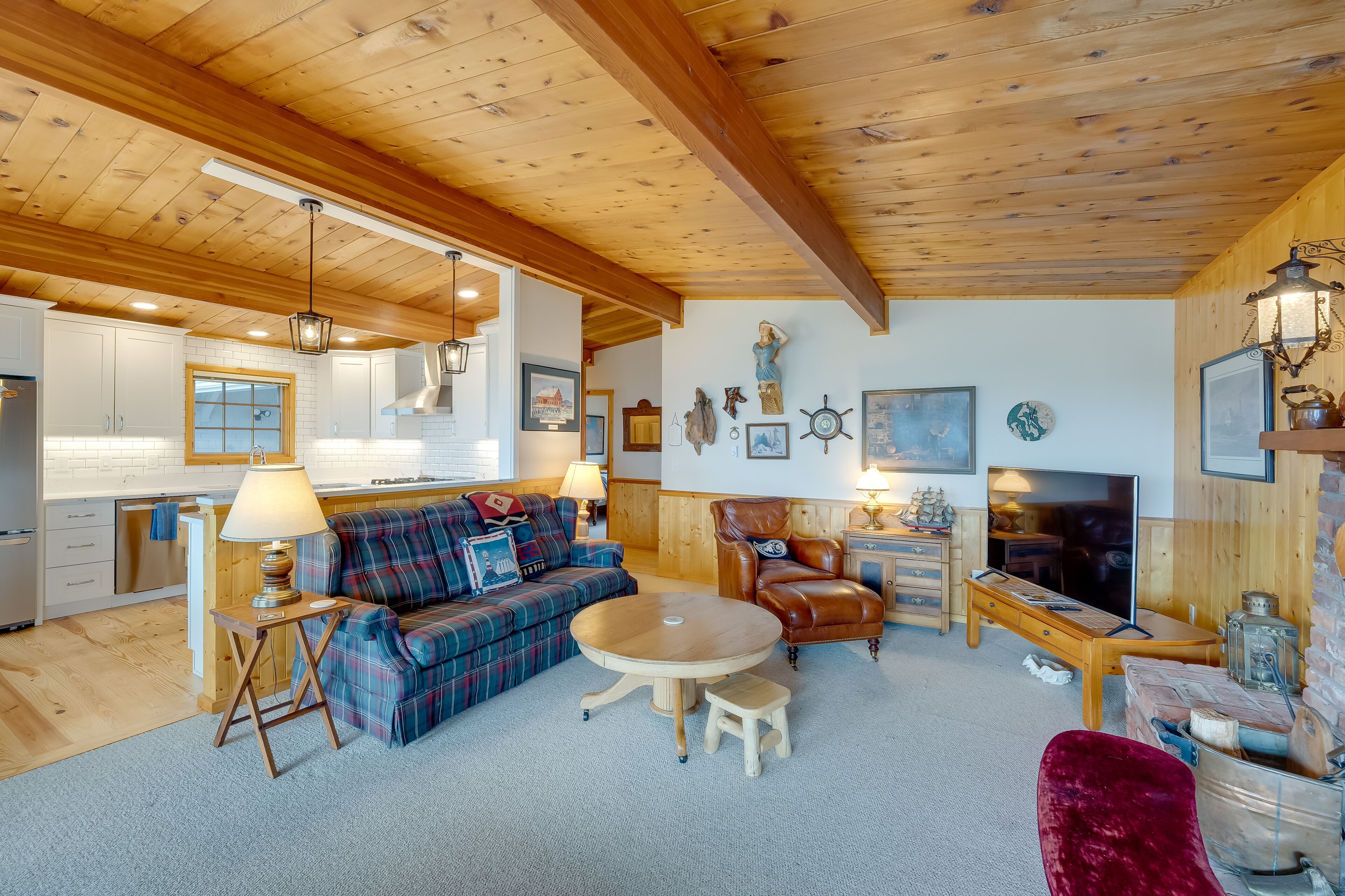 A cozy living room with a plaid sofa, a wooden coffee table, and a red velvet chair.