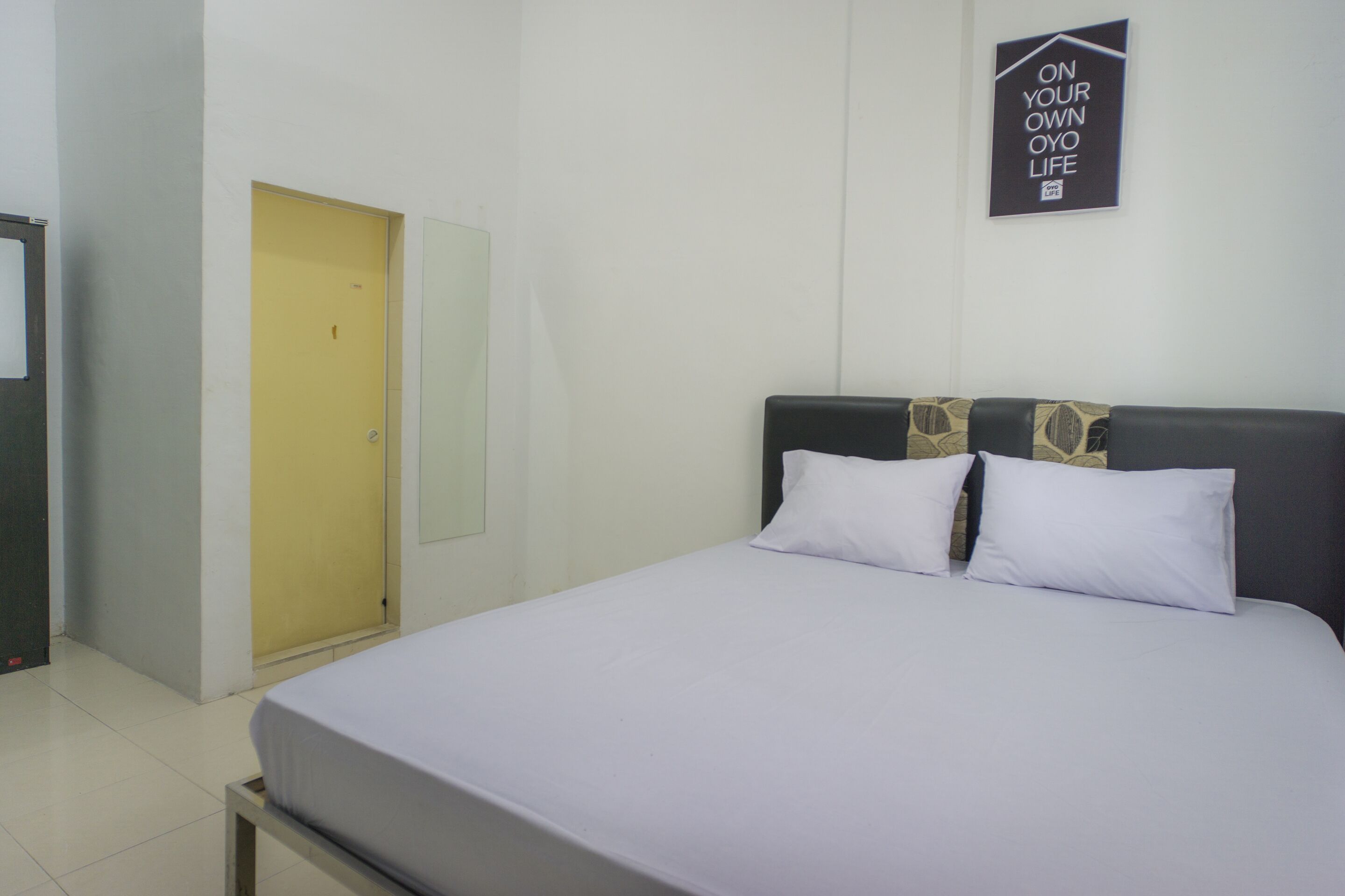 Ein Hotelzimmer mit einem Bett, einem Spiegel, einer Tür und einem motivierenden Poster an der Wand.