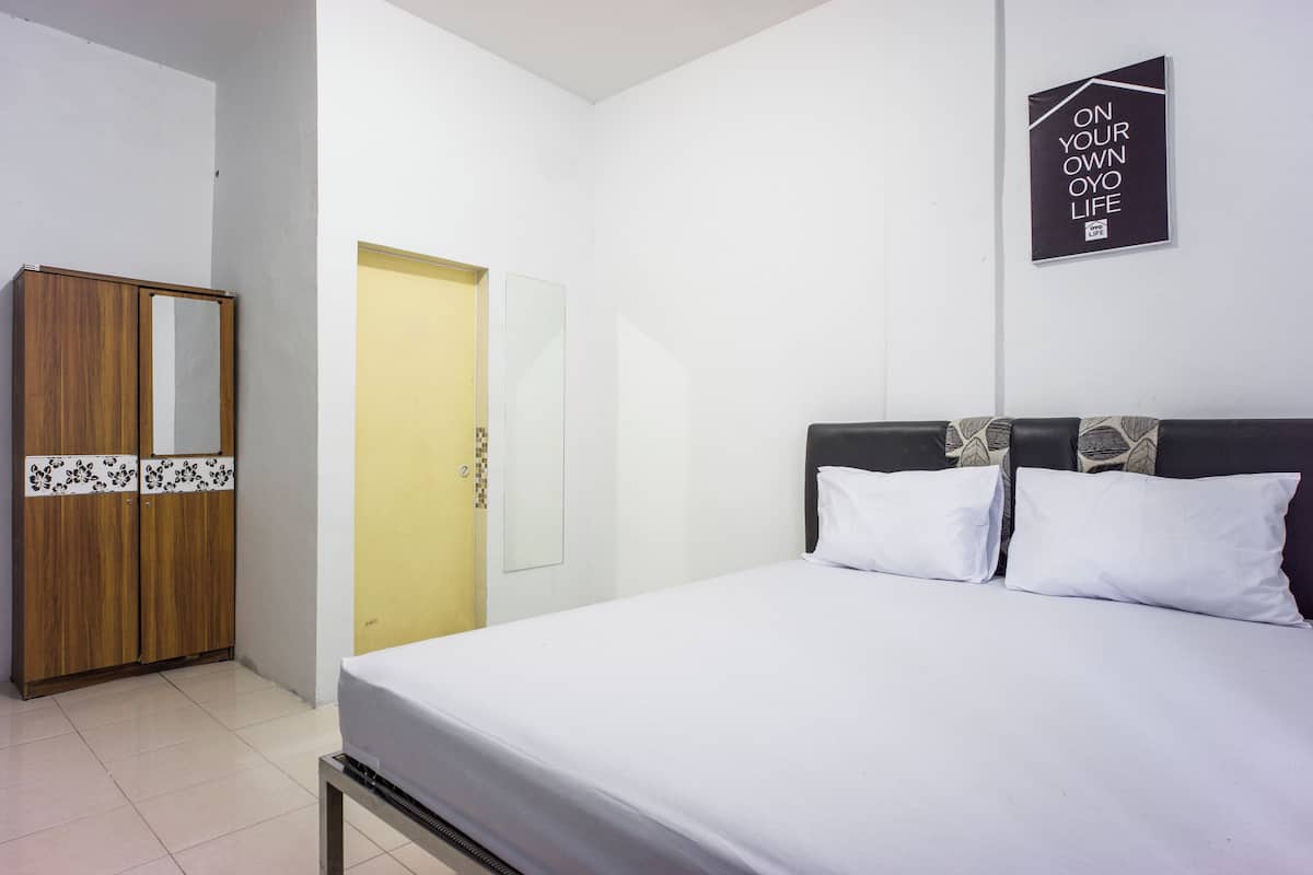 Una habitación de hotel con una cama, un armario, un espejo y una puerta.