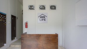 En receptionsdisk med et skilt, der viser "OYO LIFE", samt nødudgangsskiltning med nummererne 110, 113 og 118.