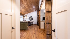 Un pasillo con piso de madera que conduce a un comedor con una araña y una pieza decorativa en la pared.