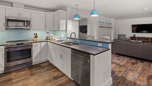 A modern kitchen with white cabinets, a built-in microwave, a dishwasher, and a granite countertop. - Tranquil Farmhouse Condo w/ Hot Tub + Dog-Friendly (Warren)