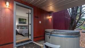 A room with a bed, a hot tub, and a door leading to another room. - Tranquil Farmhouse Condo w/ Hot Tub + Dog-Friendly (Warren)