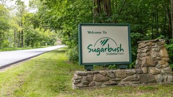 A welcome sign for Sugarbush BeBetterHere, featuring a stone wall and lush greenery.