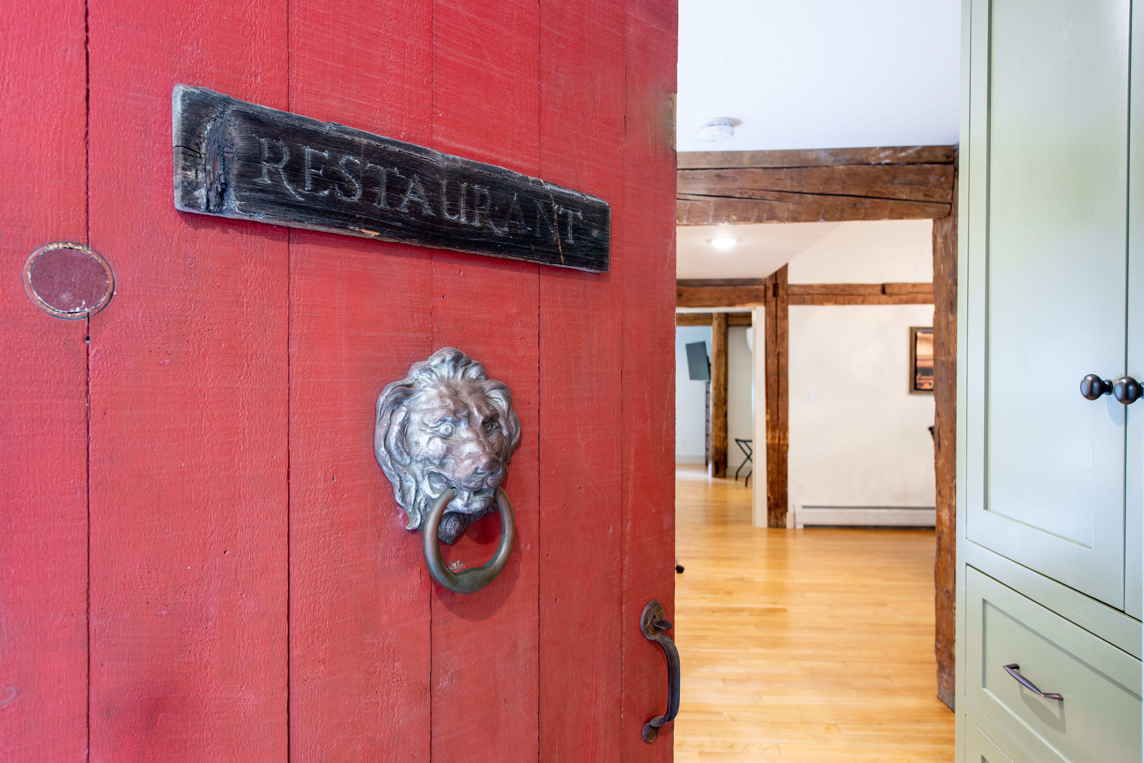 En rød dør med en løveknopper og et skilt, der står "RESTAURANT".