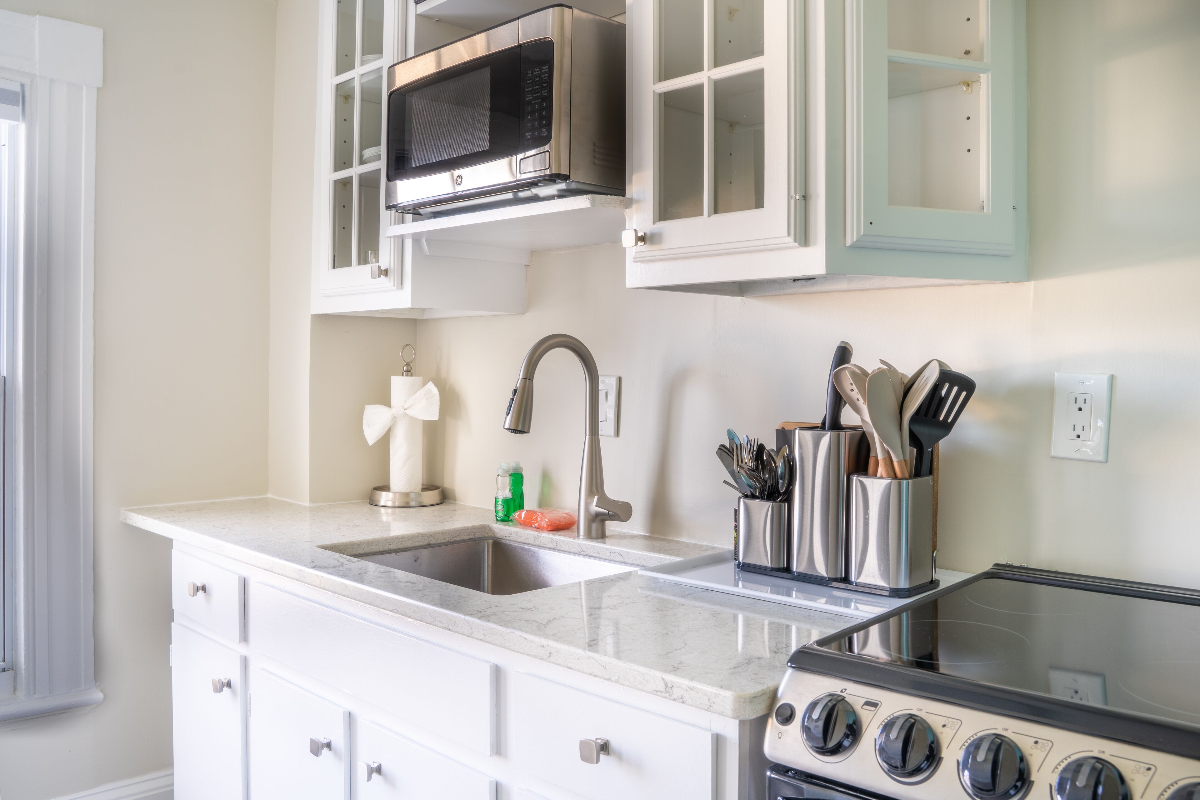 A kitchen with a built-in microwave, stainless steel sink, and a stove.