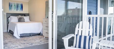 Un dormitorio con una cama, una mesita de noche y una silla junto a un ventanal corredero.
