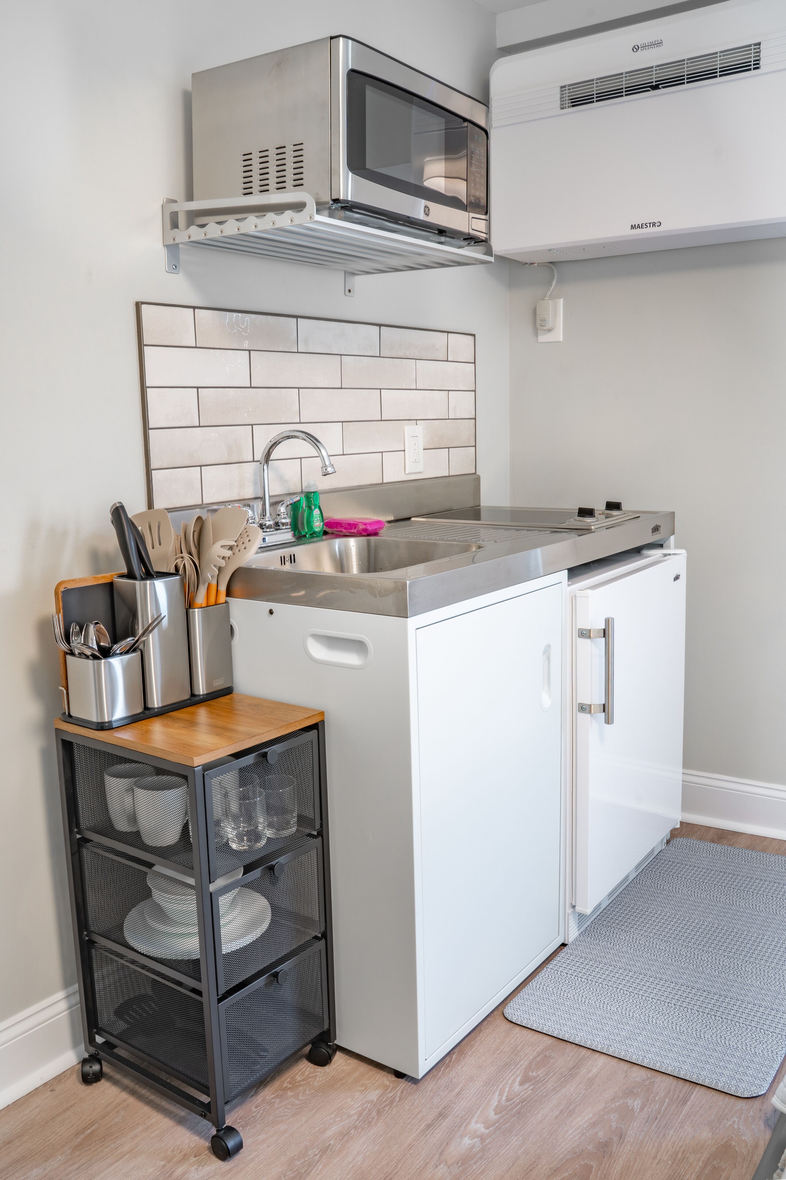 A compact kitchen with a microwave, stove, and sink.