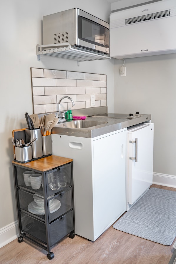 A compact kitchen with a microwave, stove, and sink. - 935 Ocean A Beachside Inn (Hampton)