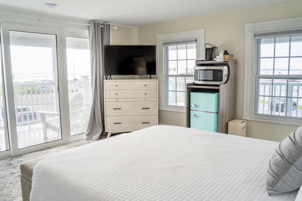A hotel room with a bed, a dresser, a television, a microwave, and a view of the outside.