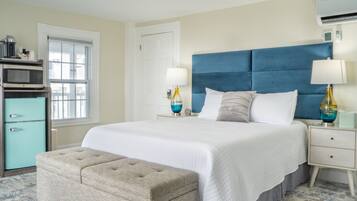 A bedroom with a large bed, a nightstand, a lamp, a dresser, and a window.
