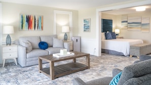 A living room with a sofa, coffee table, and a bed in the background. - 935 Ocean A Beachside Inn (Hampton)