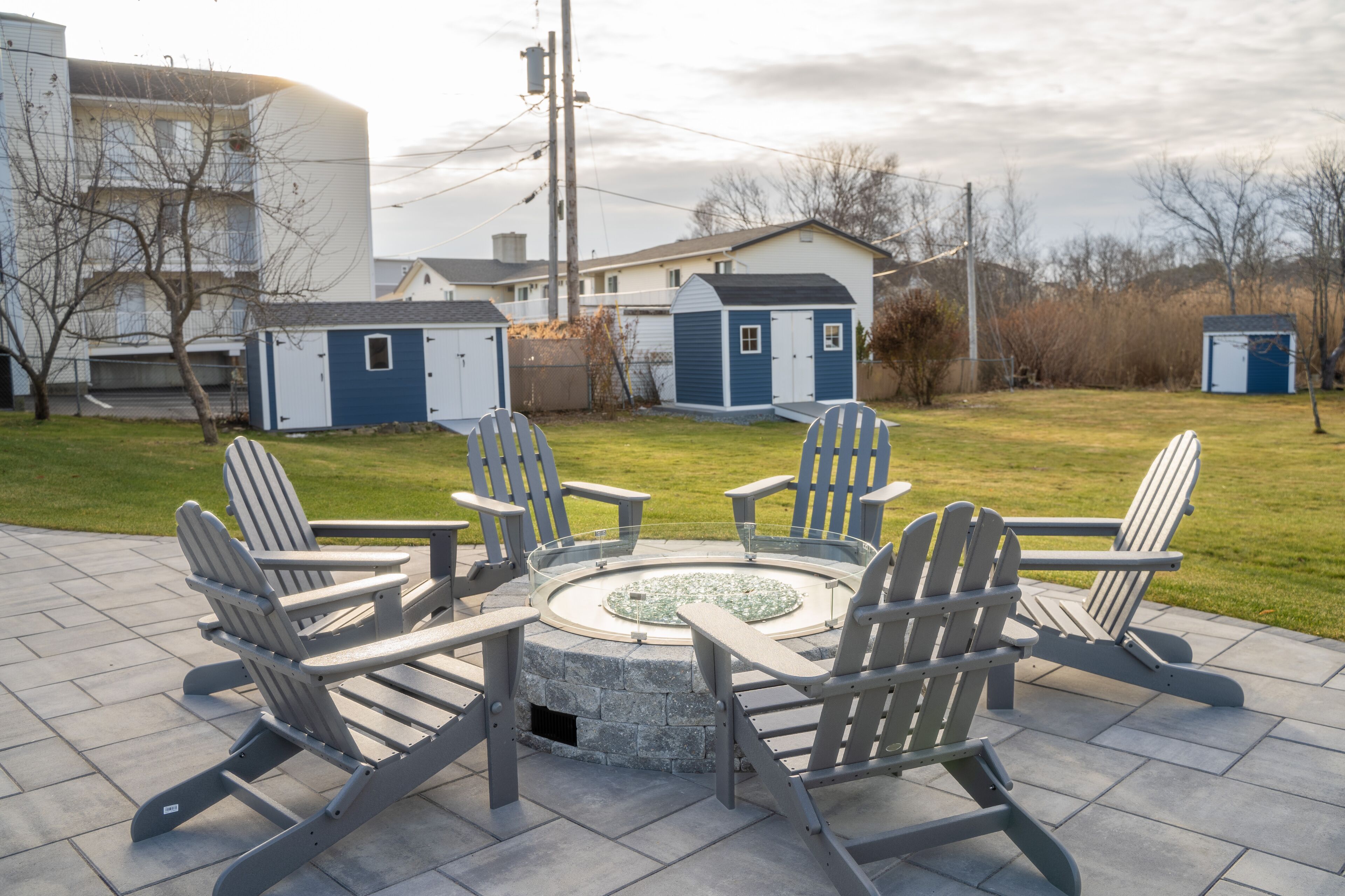 Une terrasse avec des fauteuils Adirondack disposés autour d’un foyer circulaire en pierre.
