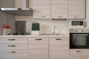 Eine moderne Küche mit hellen Holzschränken, Edelstahlgeräten und einer eingebauten Mikrowelle.
