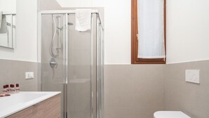 Un baño moderno con ducha de vidrio, un lavabo blanco y un inodoro.