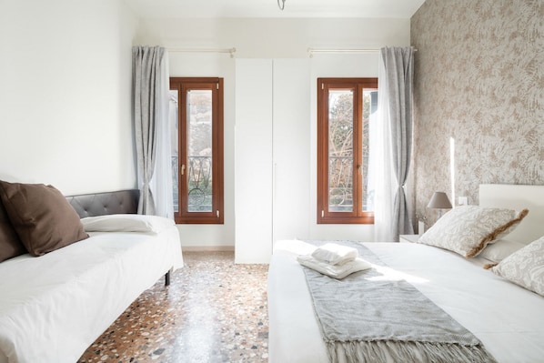 A bedroom with two beds, a patterned wall, and a view through a door. - Accademia Charm 2.2 by Wonderful Italy (Venecia)