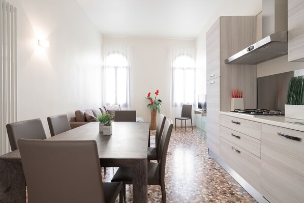 Una cucina moderna con zona pranzo, che include un tavolo grande, sedie e un piano cottura.