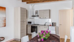 Una cocina moderna con armarios de madera clara, un microondas y un lavamanos. Hay una mesa de comedor con un florero.