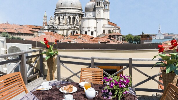 A terrace with a table set for breakfast, overlooking a historic building with domes and bell towers. - Accademia Charm 5 by Wonderful Italy (Venecia)
