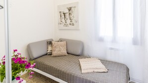 Een kleine, verzorgde slaapkamer met een bed, een kussen, een deken en een wanddecoratie.