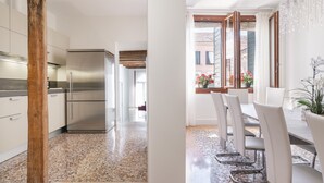 Une cuisine moderne dotée d’appareils électroménagers en acier inoxydable, d’un pilier en bois et d’un coin repas avec des chaises et une table blanches.