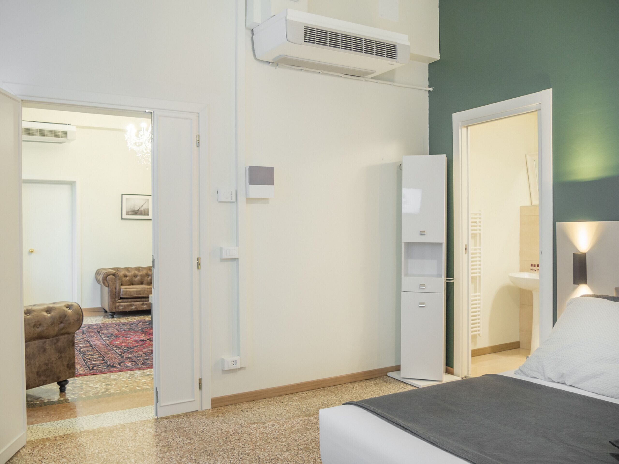 A bedroom with a bed, a wardrobe, a radiator, and a door leading to a bathroom.
