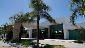 A modern building with a flat roof, large windows, and a covered entrance area. - Iloa Residence Resort Para 4 Pessoas by MME (Barra de São Miguel)