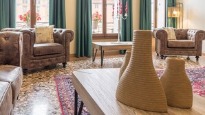 Un salon spacieux avec des fauteuils en cuir, une table basse en bois et une grande fenêtre agrémentée de rideaux.