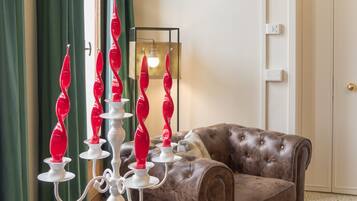 Ein Zimmer mit einem braunen Ledersofa, einer weißen Stehlampe mit roten Kerzen und einem grünen Vorhang.