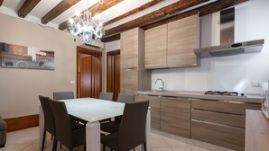 Eine moderne Küche mit Holzschränken, einem Gasherd und einem Essbereich mit Tisch und Stühlen.