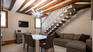 Ein Essbereich mit Tisch, Stühlen, einer Couch, einem Fernseher und einer Treppe.