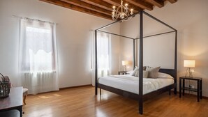 A four-poster bed with a wooden frame, two bedside tables with lamps, a wooden floor, and a chandelier. - Herion Palace Apt. 2 by Wonderful Italy (Venecia)