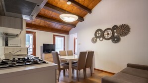 A modern kitchen with a gas stove, dining table with chairs, and a TV in the background. - Herion Palace Apt. 2 by Wonderful Italy (Venecia)