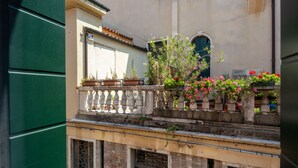 A balcony with potted plants and flowers, a white balustrade, and a view of a building with a tiled roof. - Herion Palace Apt. 2 by Wonderful Italy (Venecia)