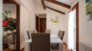 Un comedor con una mesa, sillas, una planta en maceta y obras de arte en la pared.