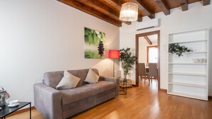 Una sala de estar moderna con un sofá gris, una lámpara de pie roja, suelo de madera y un ventanal grande.