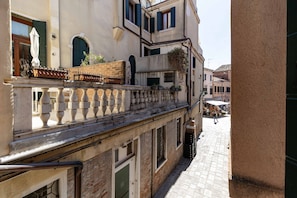 Una calle estrecha con edificios que tienen balcones, adoquinado y un cielo despejado.